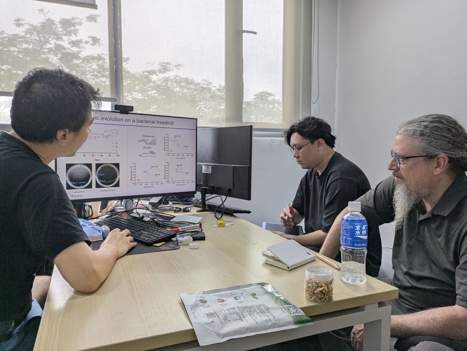 Oron Catts and researchers discussing data from a bacterial evolution experiment