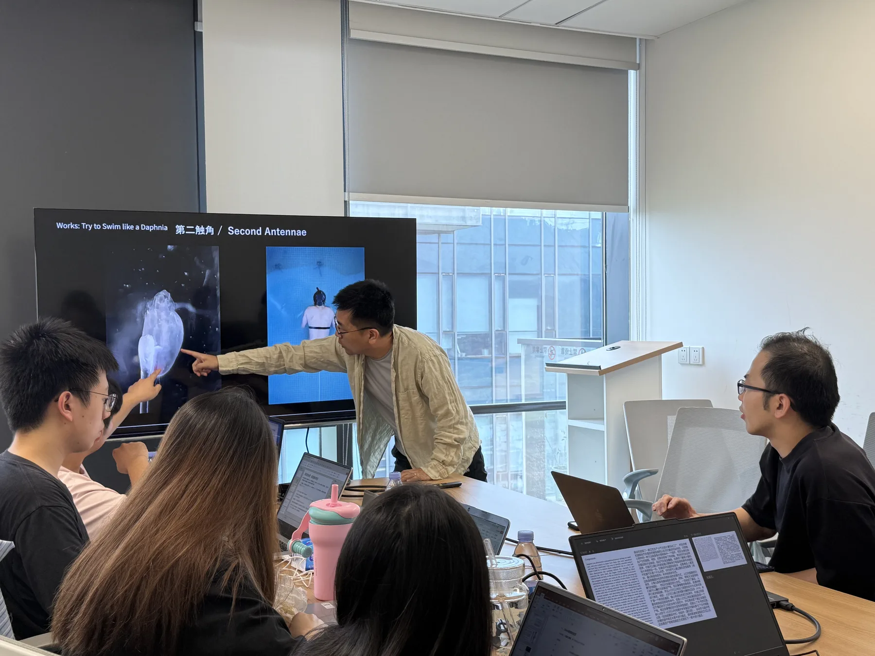 Tomoki Matsumura presenting a daphnia-inspired artwork during a research group meeting